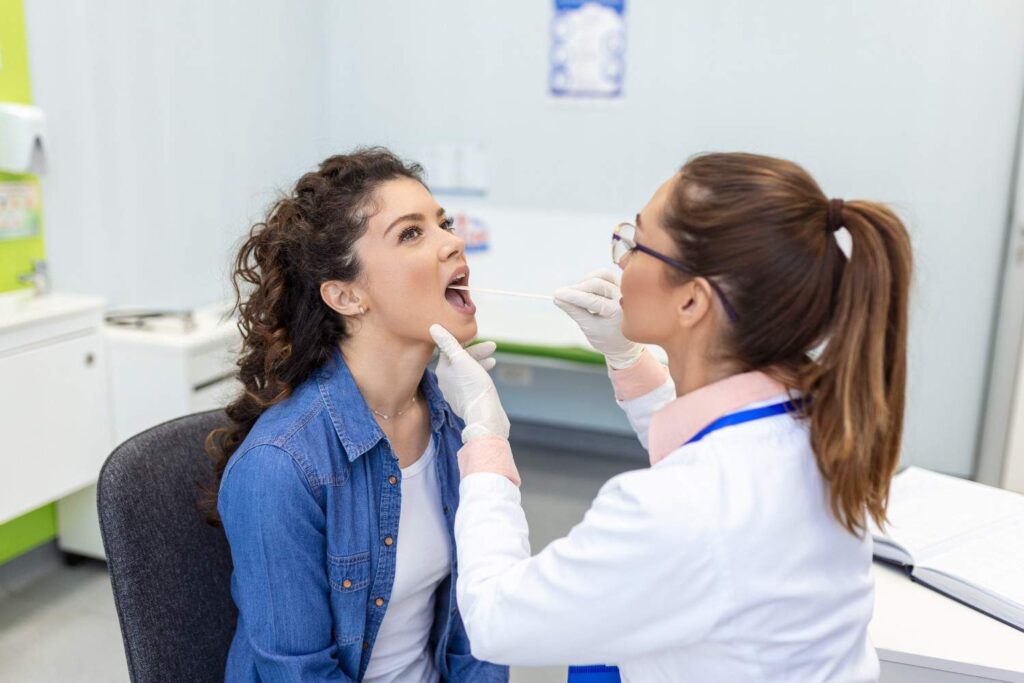 doctor-with-depressor-checking-sore-throat-experienced-doctor-examines-adult-woman-sore-throat (1)